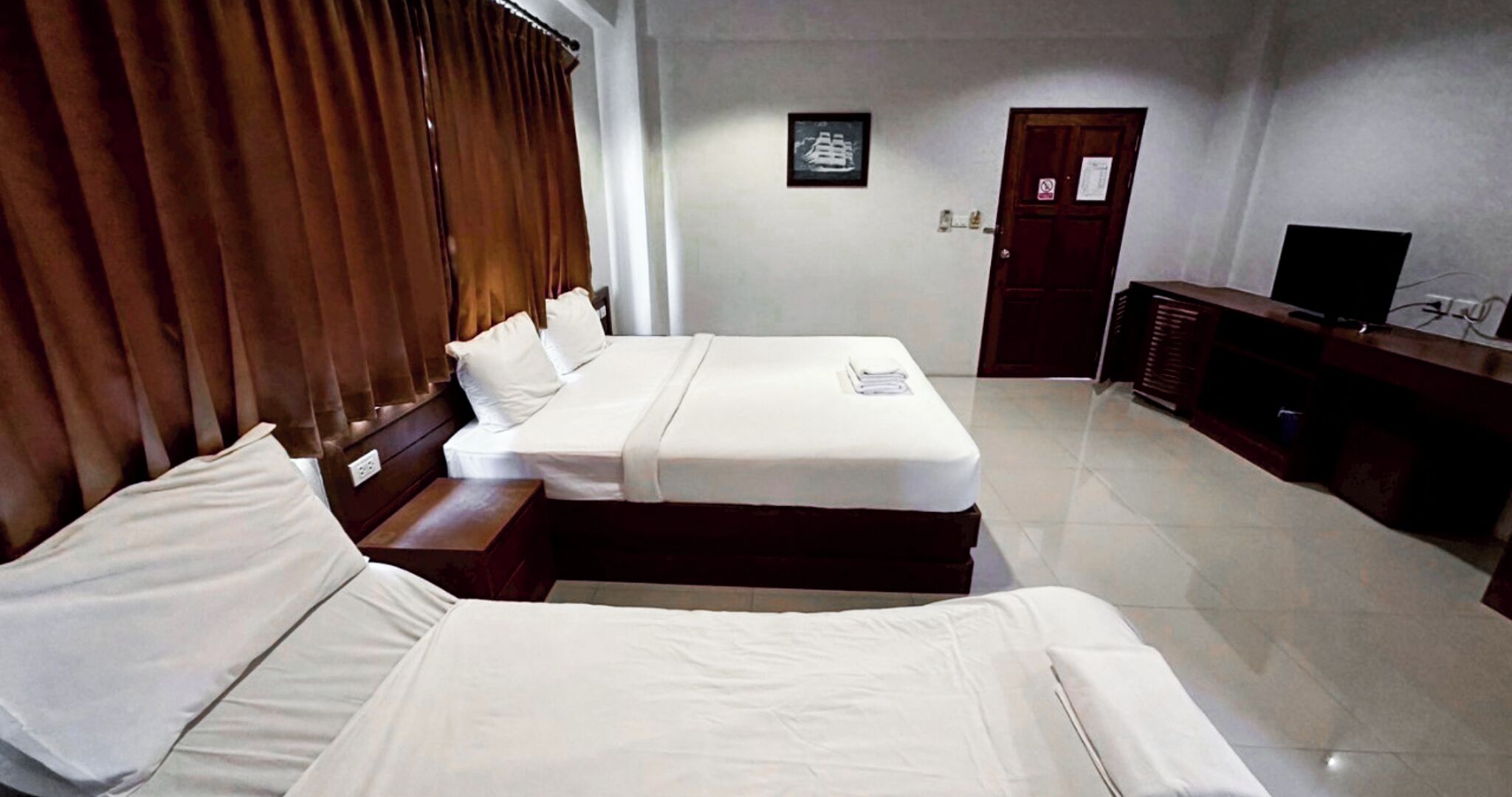 Een hotelkamer met een bed, een bureau, een televisie en een deur.
