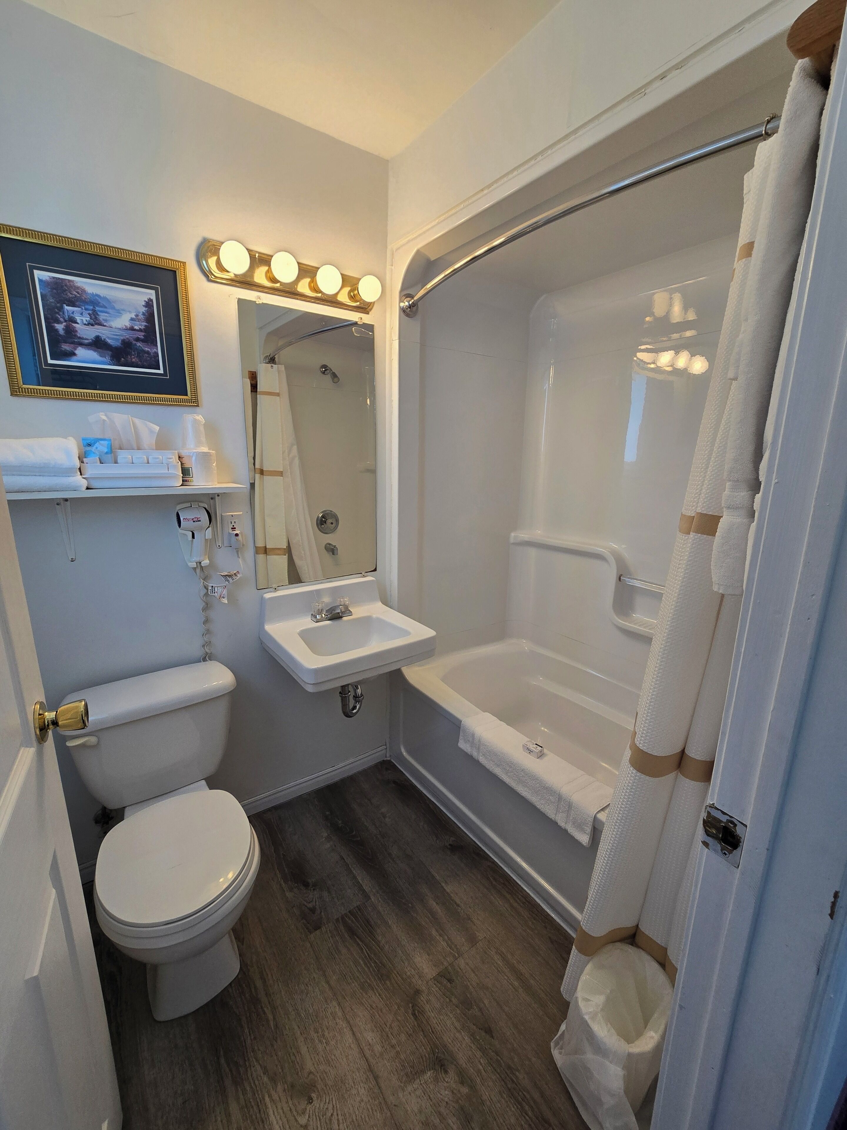 A compact bathroom with a toilet, sink, and shower.