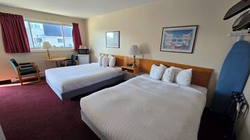 Habitación de hotel con dos camas, un escritorio, una silla, un microondas, una lámpara, un cuadro en la pared y una tabla de snowboard apoyada contra la pared.