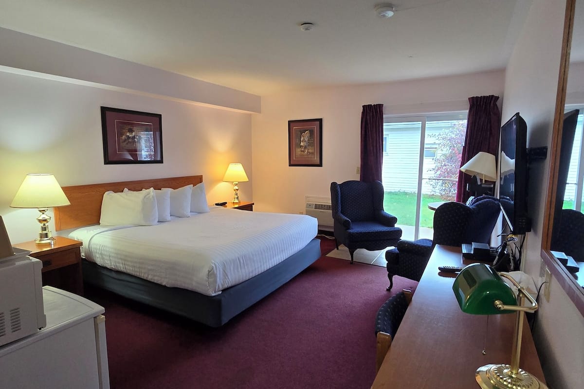 Een hotelkamer met een bed, een bureau, een stoel, een televisie en een raam met gordijnen.