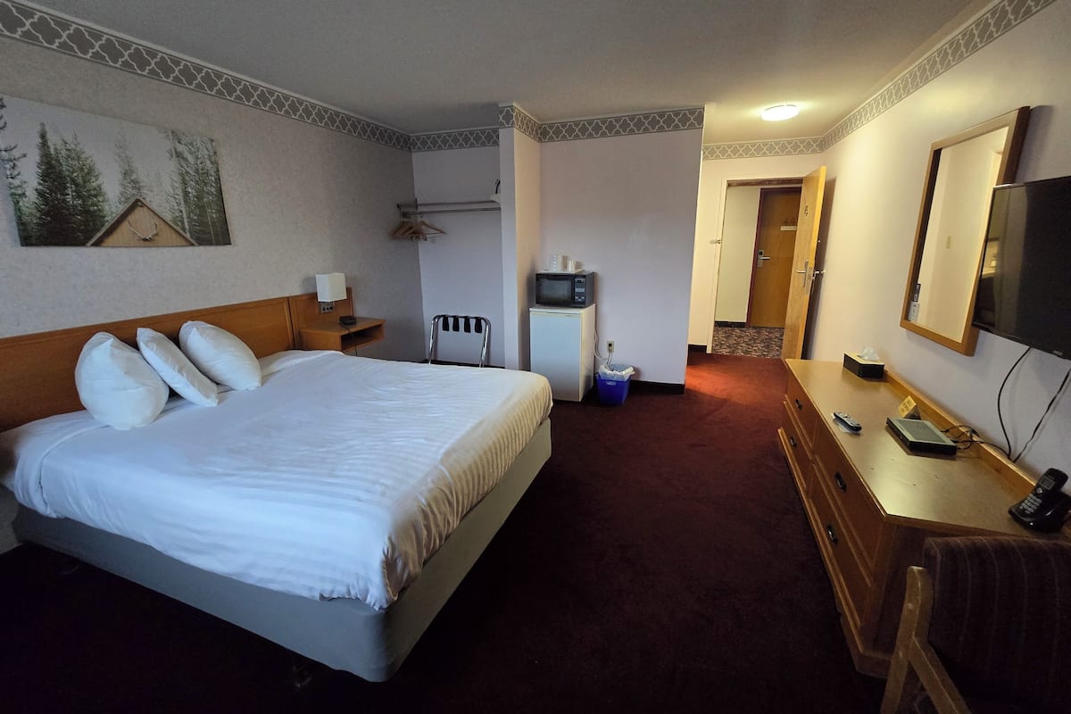 Een hotelkamer met een bed, nachtkastje, televisie en een bureau met stoel.