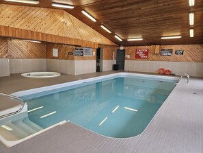 Une piscine intérieure avec des murs et un plafond en bois, une eau claire et des panneaux de signalisation de sécurité.