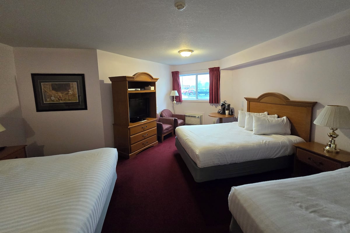 Hotelkamer met twee bedden, een bureau met stoel, een televisie en een raam met gordijnen.