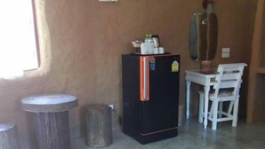 Una habitación compacta con un refrigerador negro, una pequeña mesa de madera y dos sillas.