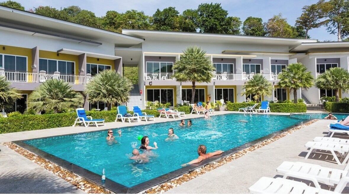 A swimming pool area with lounge chairs and a building with balconies.
