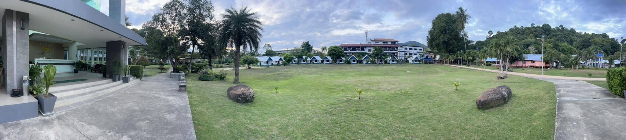 A hotel with a spacious lawn, a reception area, and a building with multiple windows.