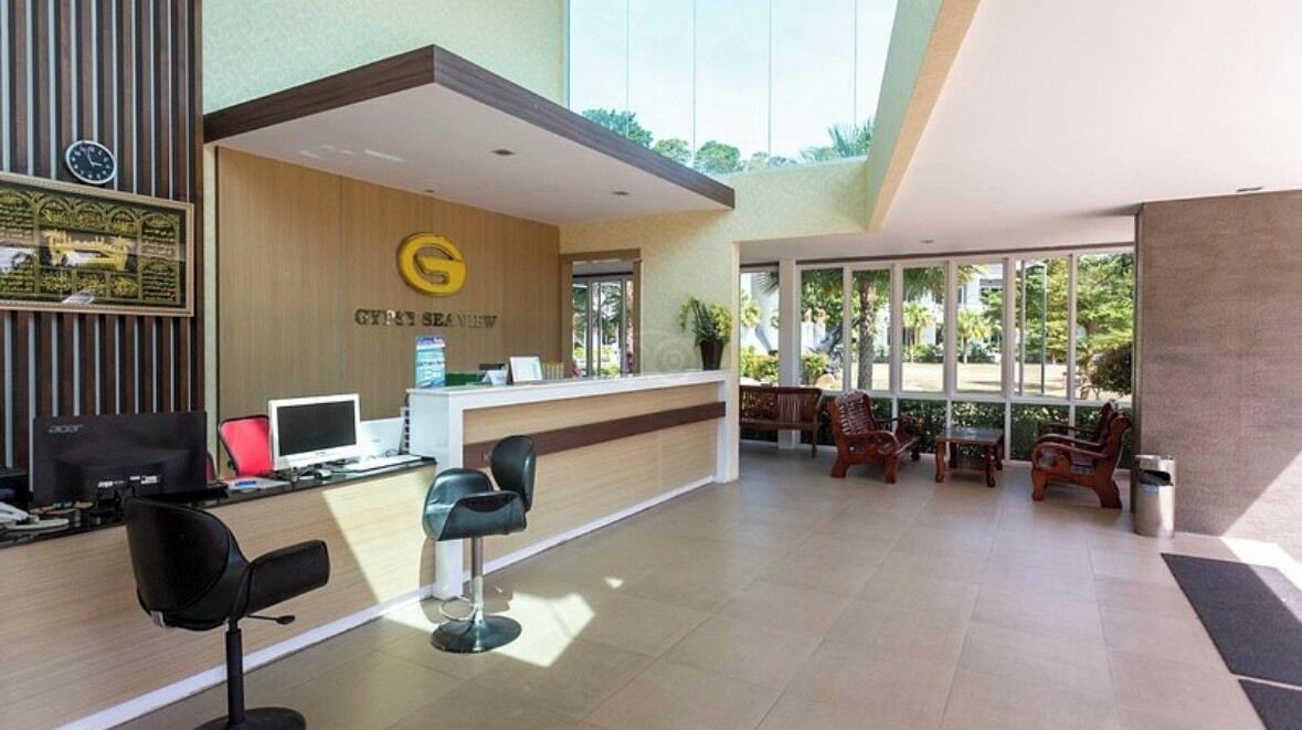A reception area with a wooden reception desk, a computer, and two black chairs.