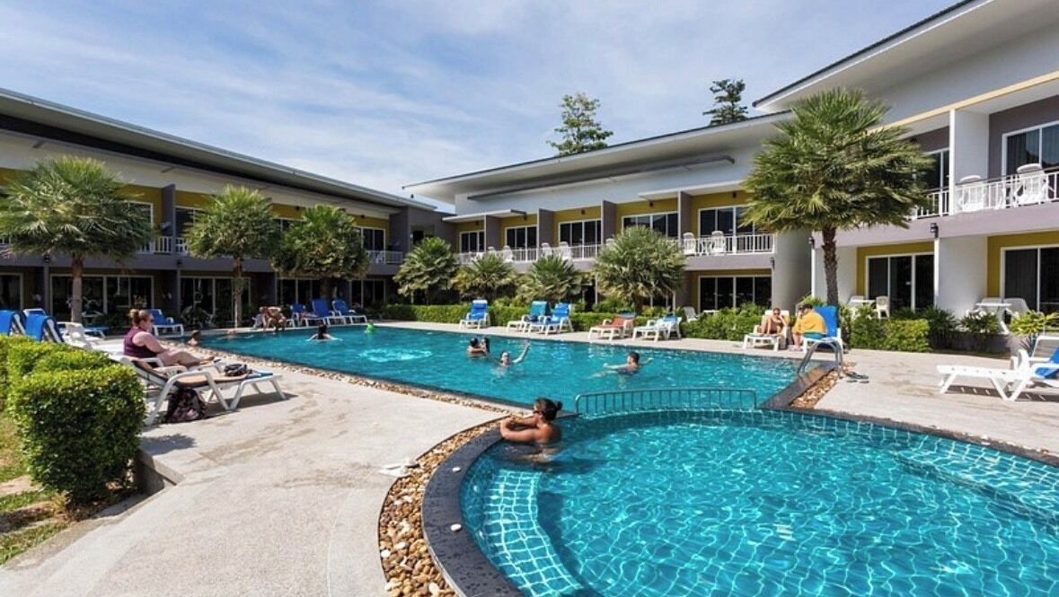A hotel pool area with multiple pools, lounge chairs, and palm trees.