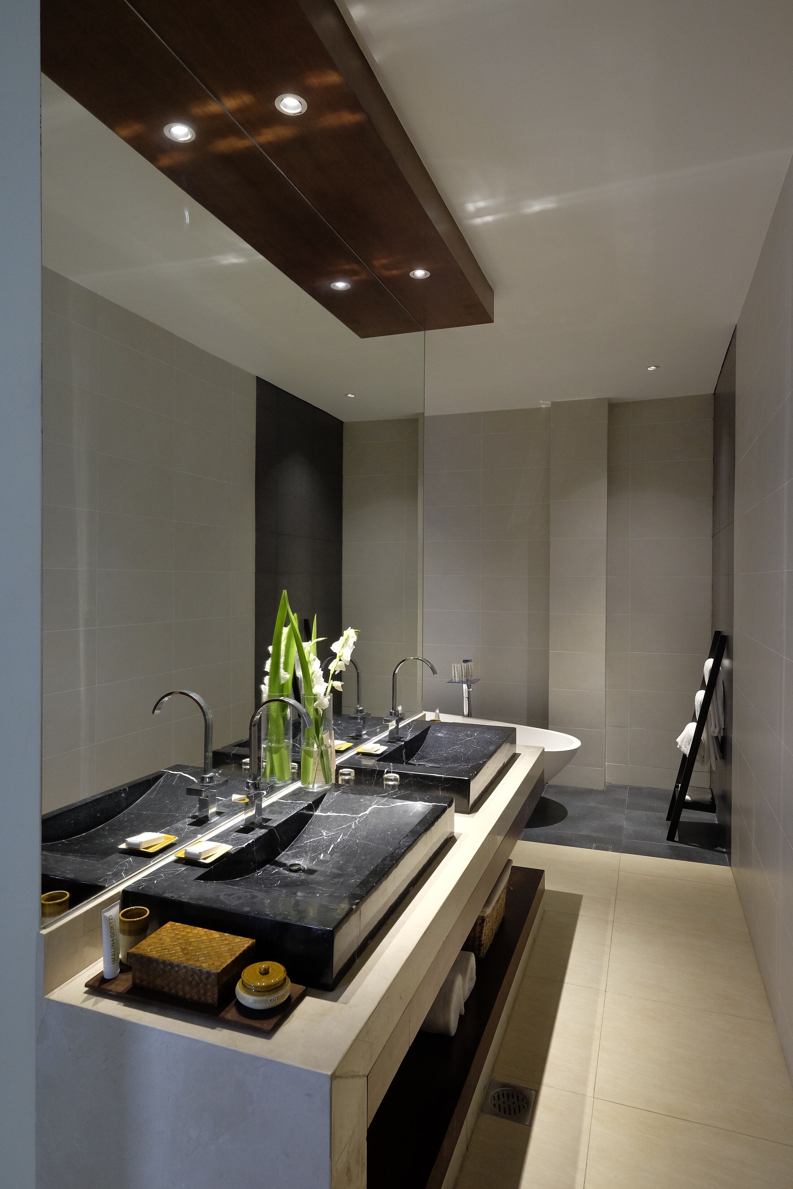 A modern bathroom with two sinks, a large mirror, and a shower area.