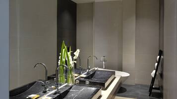 A modern bathroom with two sinks, a large mirror, and a shower area.