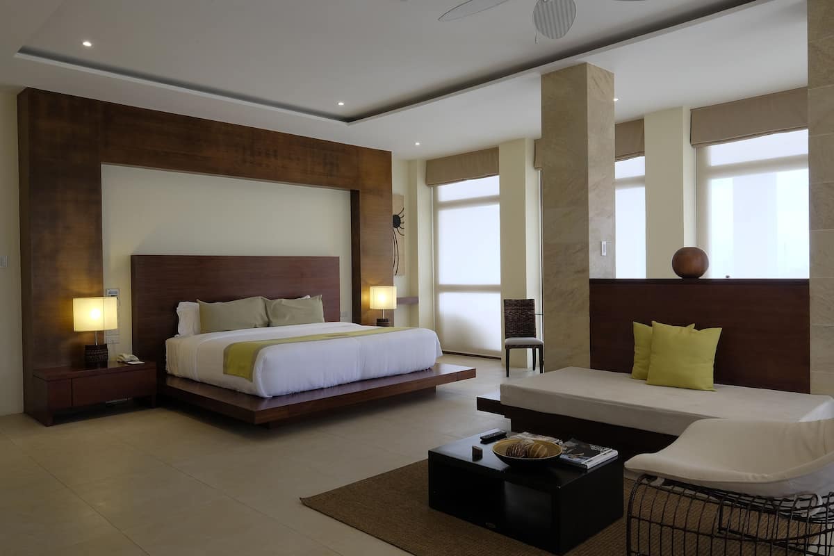 Une chambre d’hôtel moderne avec un grand lit, un canapé, une table basse et un fauteuil.