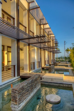 Un hotel moderno con zona de piscina, que incluye una fuente de agua y una terraza de madera.