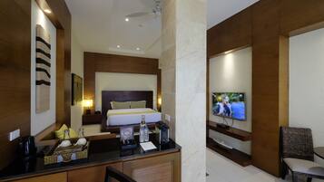 A hotel room with a bed, a desk with a computer, a TV, and a chair.