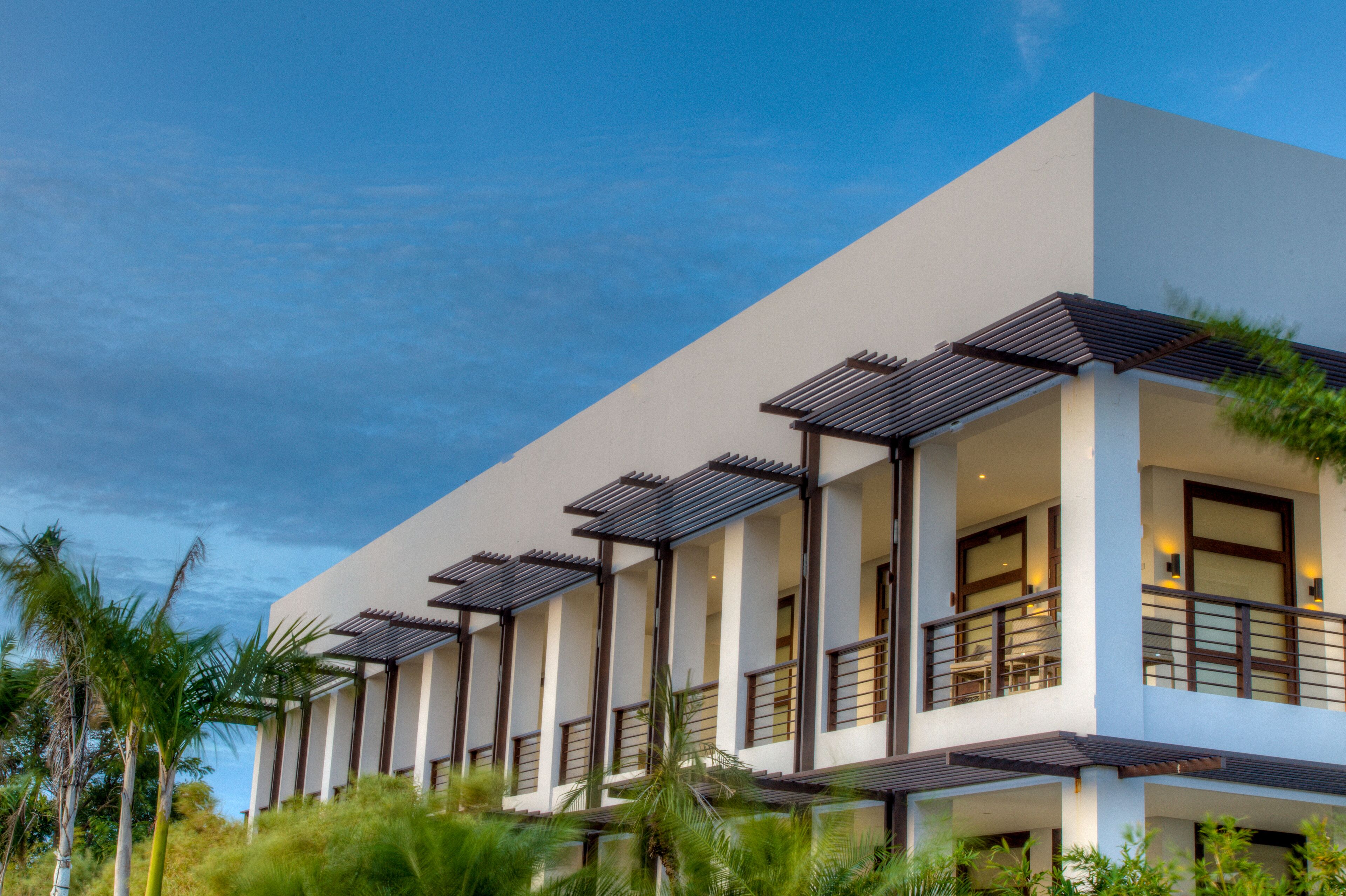 A modern hotel with multiple balconies, large windows, and a flat roof design.