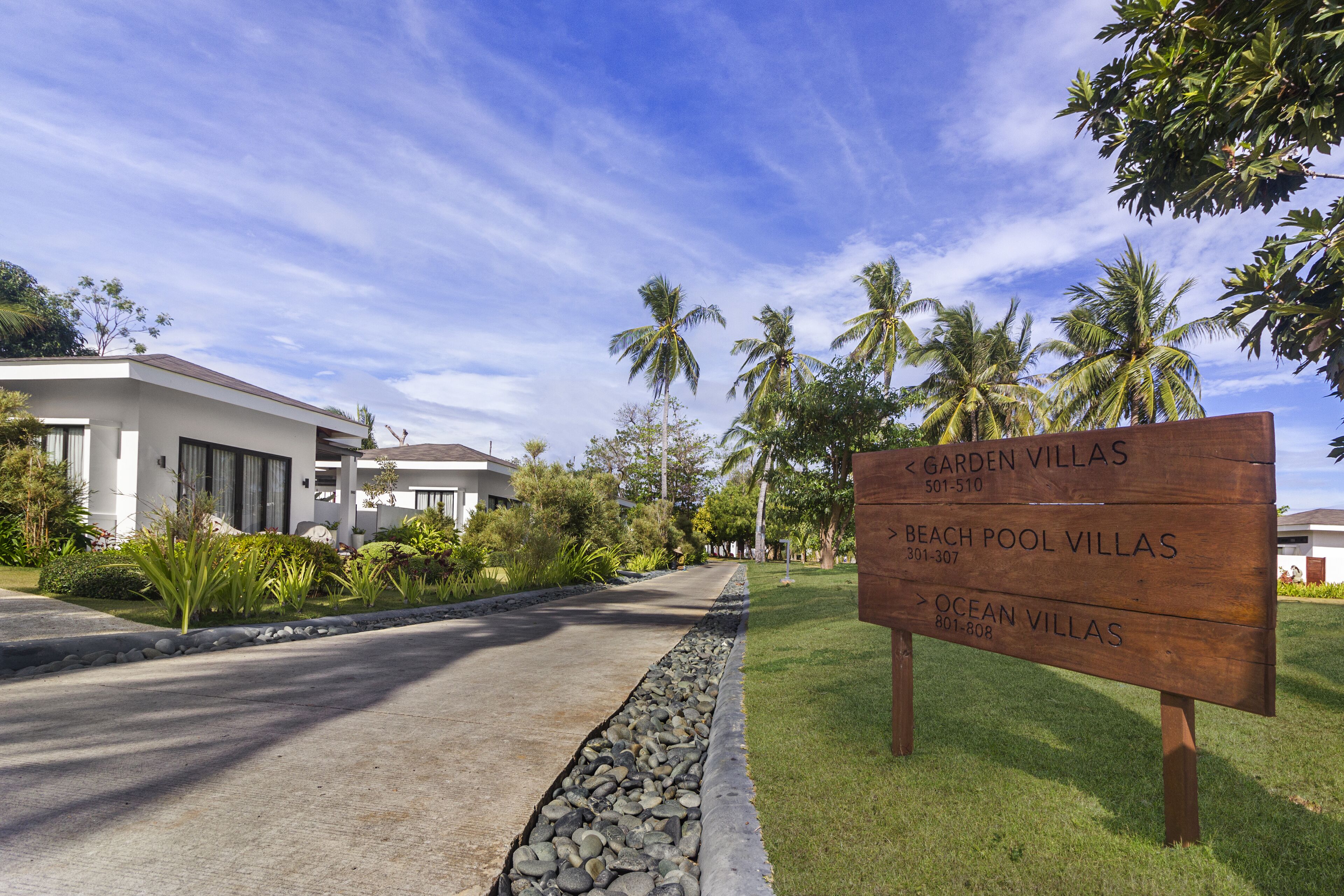 A signboard for Garden Villas, Beach Pool Villas, and Ocean Villas with contact numbers.