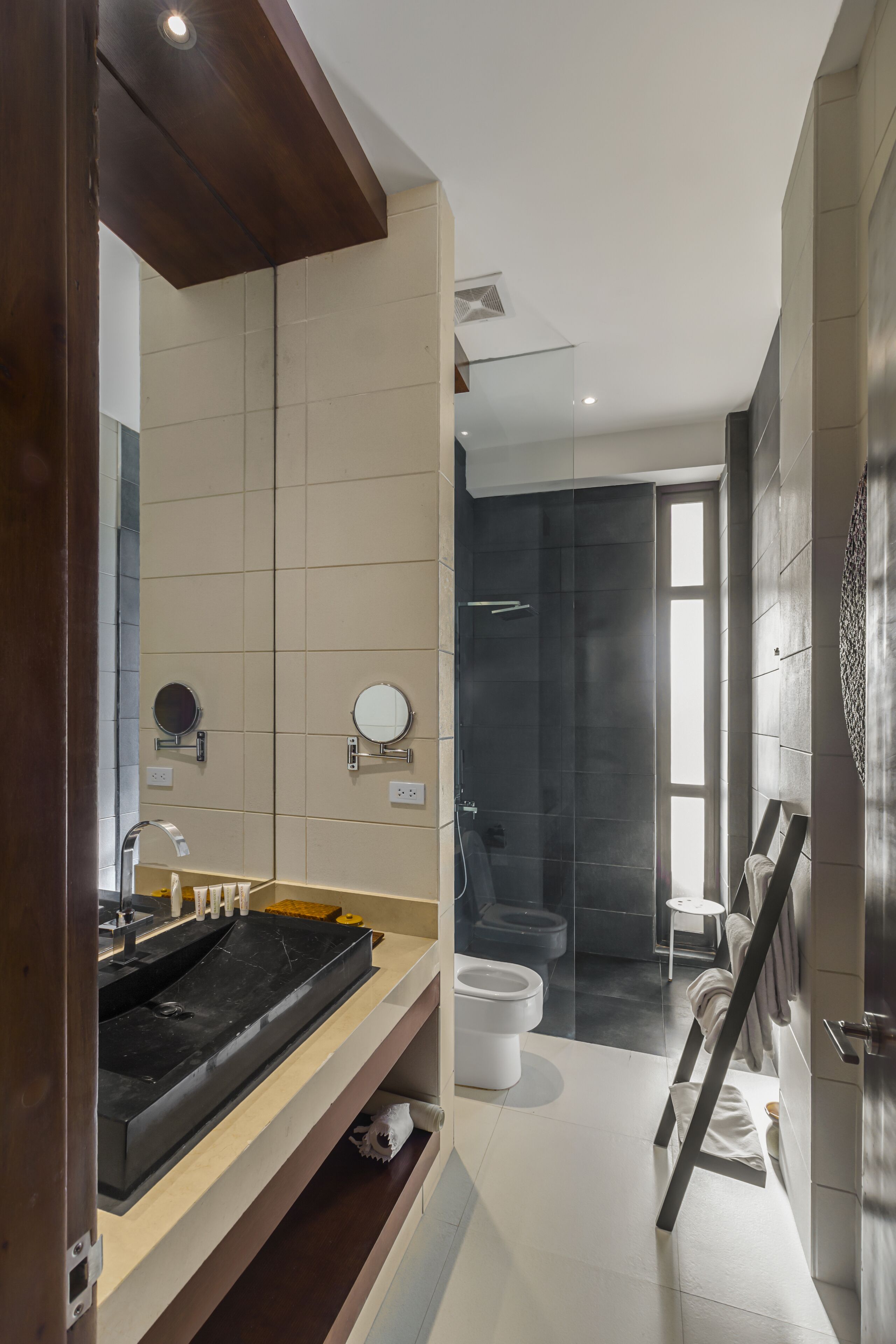 A modern bathroom with a large mirror, a black sink, and a shower area.