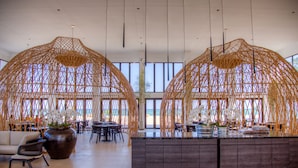 Een ruime binnenruimte met een centraal eiland, zithoeken en grote ramen voor natuurlijk licht.