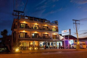 A multi-story hotel with a covered outdoor area, a signboard, and a bus in front. - Krabi More Hotel (Krabi)