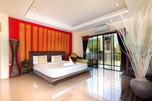 A modern bedroom with a large bed, a sofa, a decorative vase, and a view of the outdoors. - Krabi More Hotel (Krabi)
