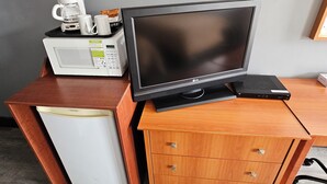 A compact kitchenette with a microwave, coffee maker, and a laptop on a wooden cabinet. - Forest Plaza Motel (Wellington North)