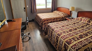 A hotel room with two beds, a desk, a chair, a lamp, and a window with curtains. - Forest Plaza Motel (Wellington North)