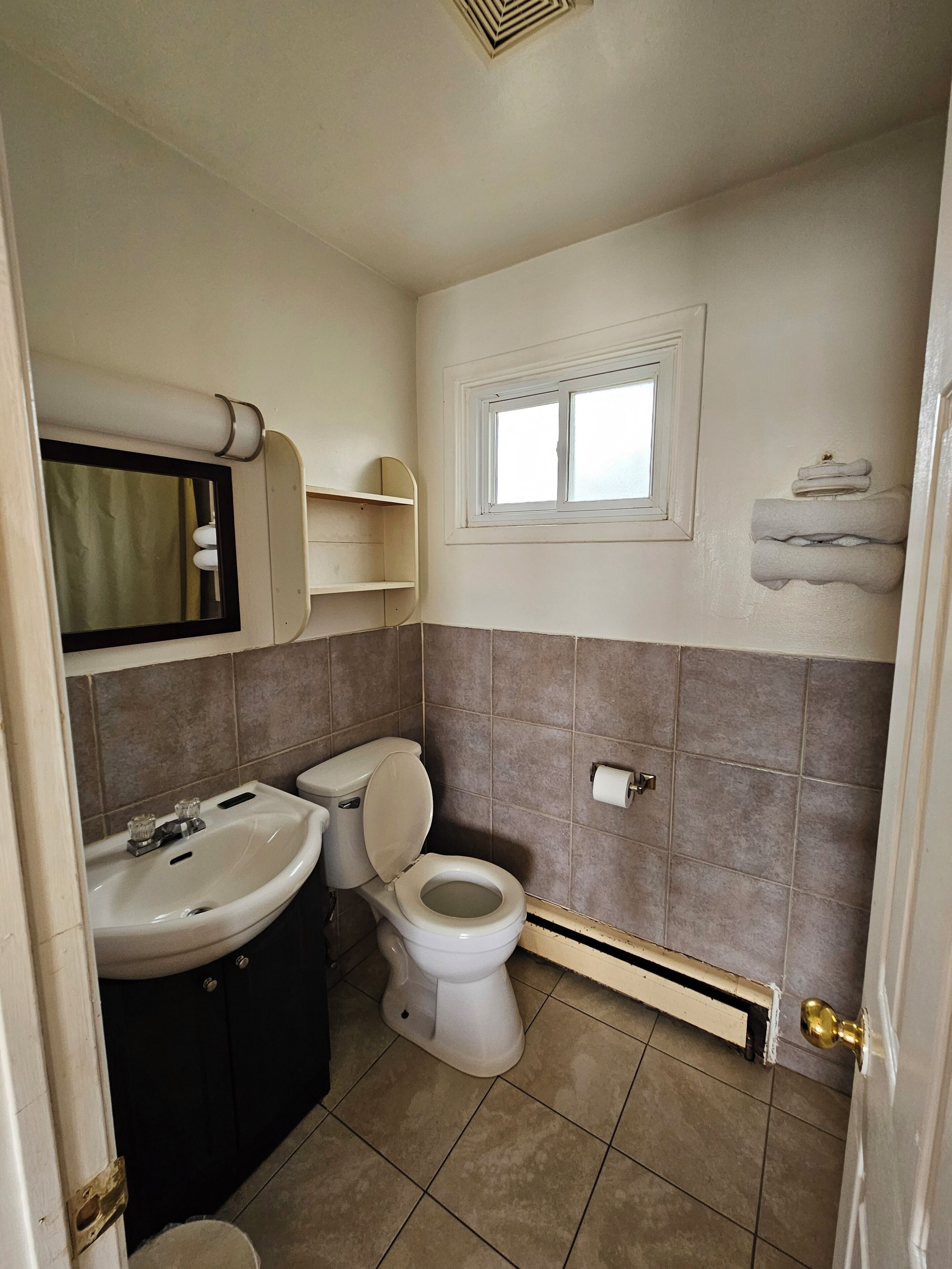 Un baño con inodoro, lavamanos y ventana.