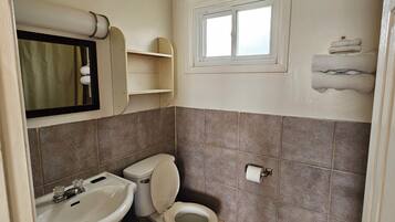 Un baño con inodoro, lavamanos y ventana.