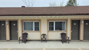 A building with three doors labeled 102, 103, and 104. There are two chairs in front of the building. - Forest Plaza Motel (Wellington North)