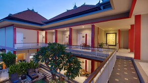 A hotel with a pool, multiple balconies, and a well-lit interior. - Angkul Angkul Beach In Kuta (Kuta)
