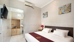 A hotel room with a large bed, a TV mounted on the wall, a wooden wardrobe, a bathroom with a mirror, and a painting on the wall. - Angkul Angkul Beach In Kuta (Kuta)