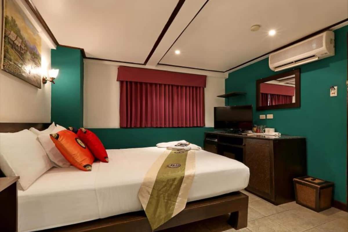 Una habitación de hotel con cama, televisor, escritorio y aire acondicionado.
