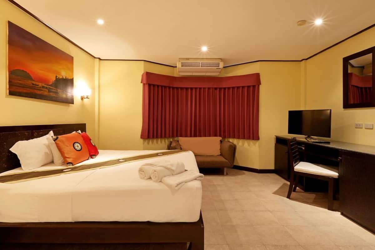 Habitación de hotel con cama, escritorio, silla, televisor y un cuadro en la pared.