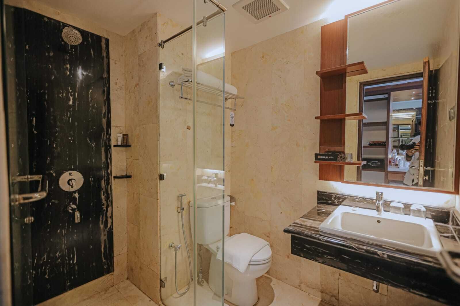 A modern bathroom with a glass-enclosed shower, a white toilet, and a marble sink.
