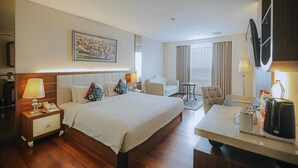 Una habitación de hotel con una cama grande, un escritorio, una silla, un televisor y un cuadro en la pared.