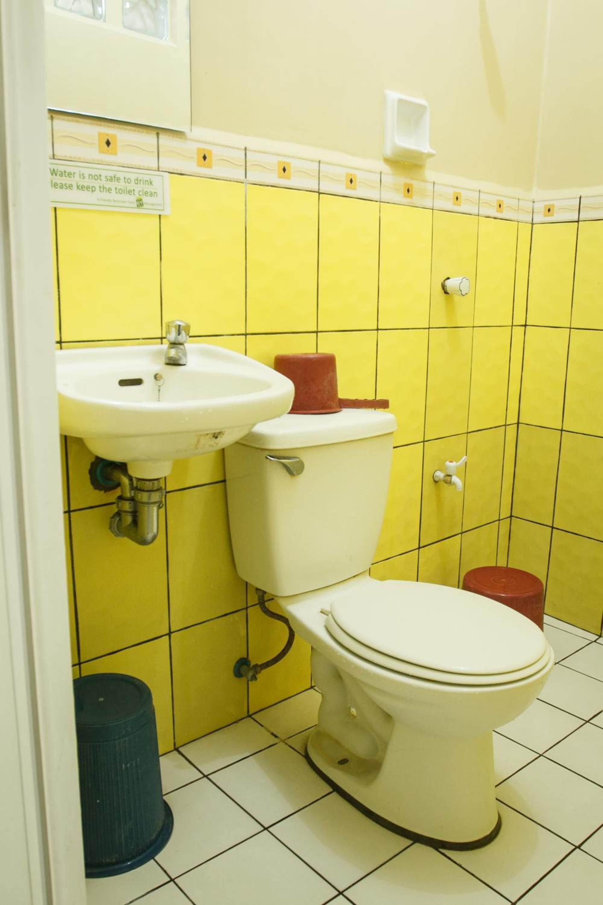 A bathroom with yellow tiles, a white sink, and a white toilet.