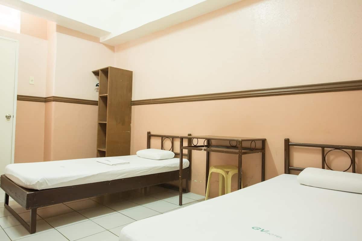 A room with two single beds, a wooden wardrobe, and a small stool.