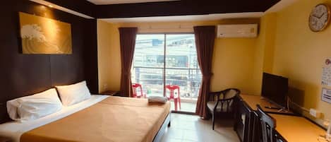 Habitación de hotel con cama, escritorio con silla, televisión y vista al exterior.