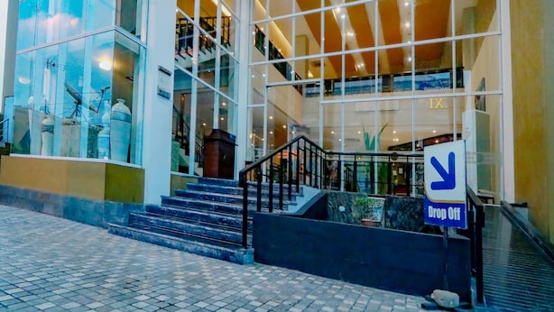 Un edificio moderno con grandes ventanales, una escalera y un letrero que dice 'Drop Off'.