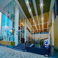 Un edificio moderno con grandes ventanales, una escalera y un letrero que dice 'Drop Off'.