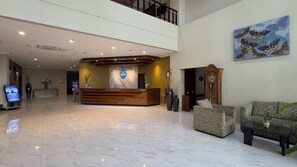A hotel lobby with a reception desk, a large clock, and a seating area with patterned sofas. - Hotel Dafam Pekalongan (Pekalongan)