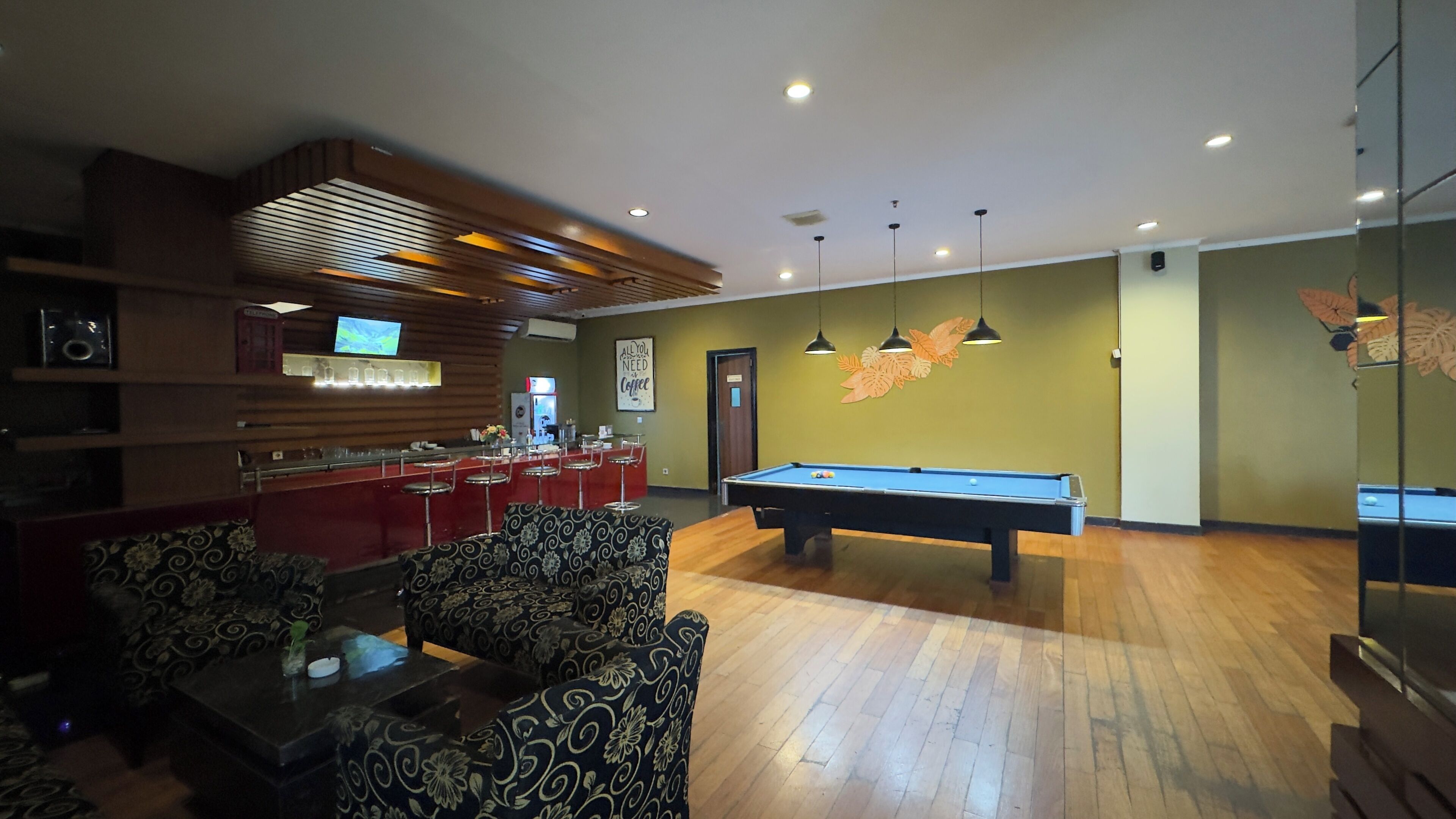 A billiards room with a pool table, bar area, and seating.