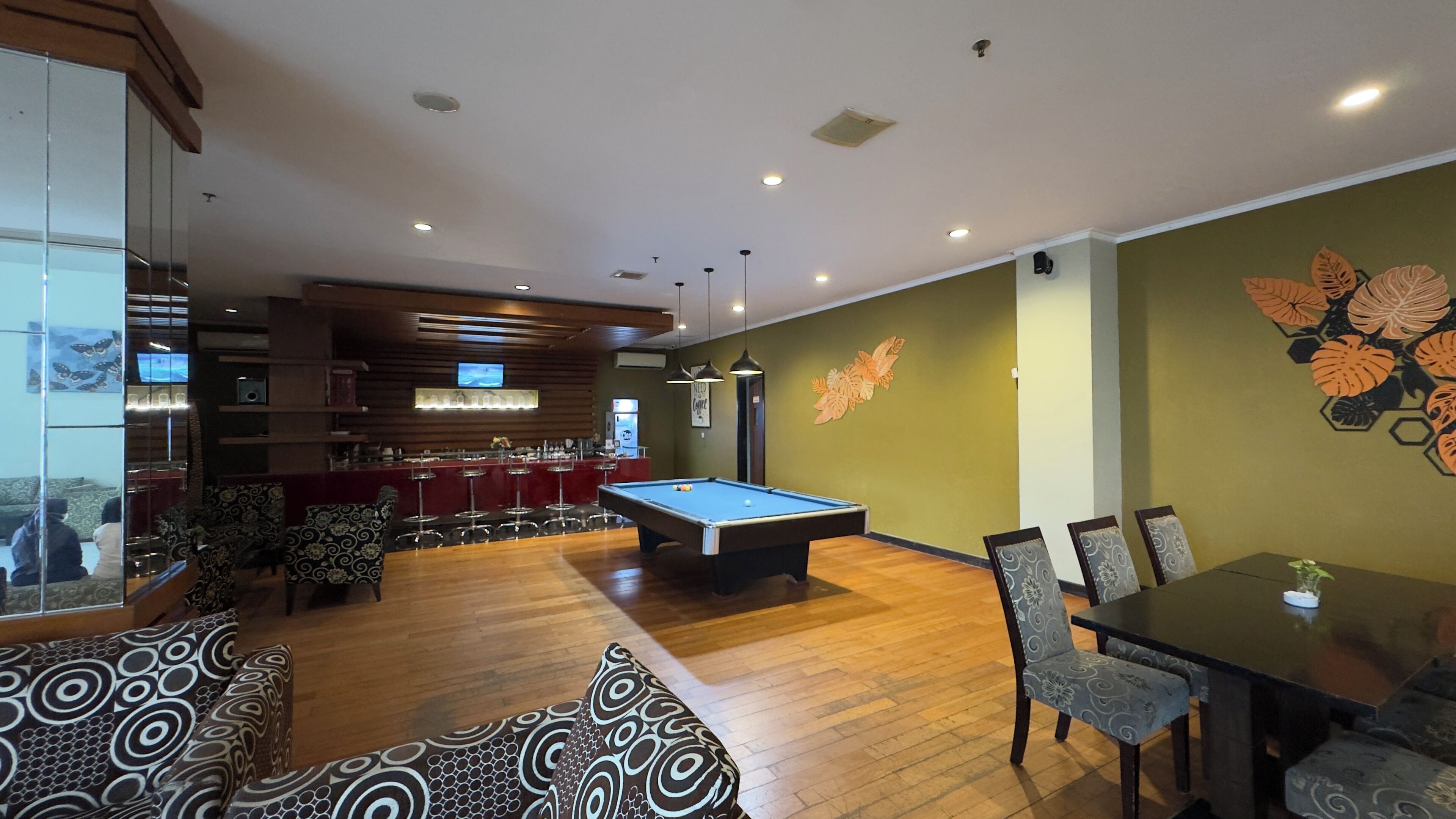 A billiards room with a pool table, bar area, and seating.