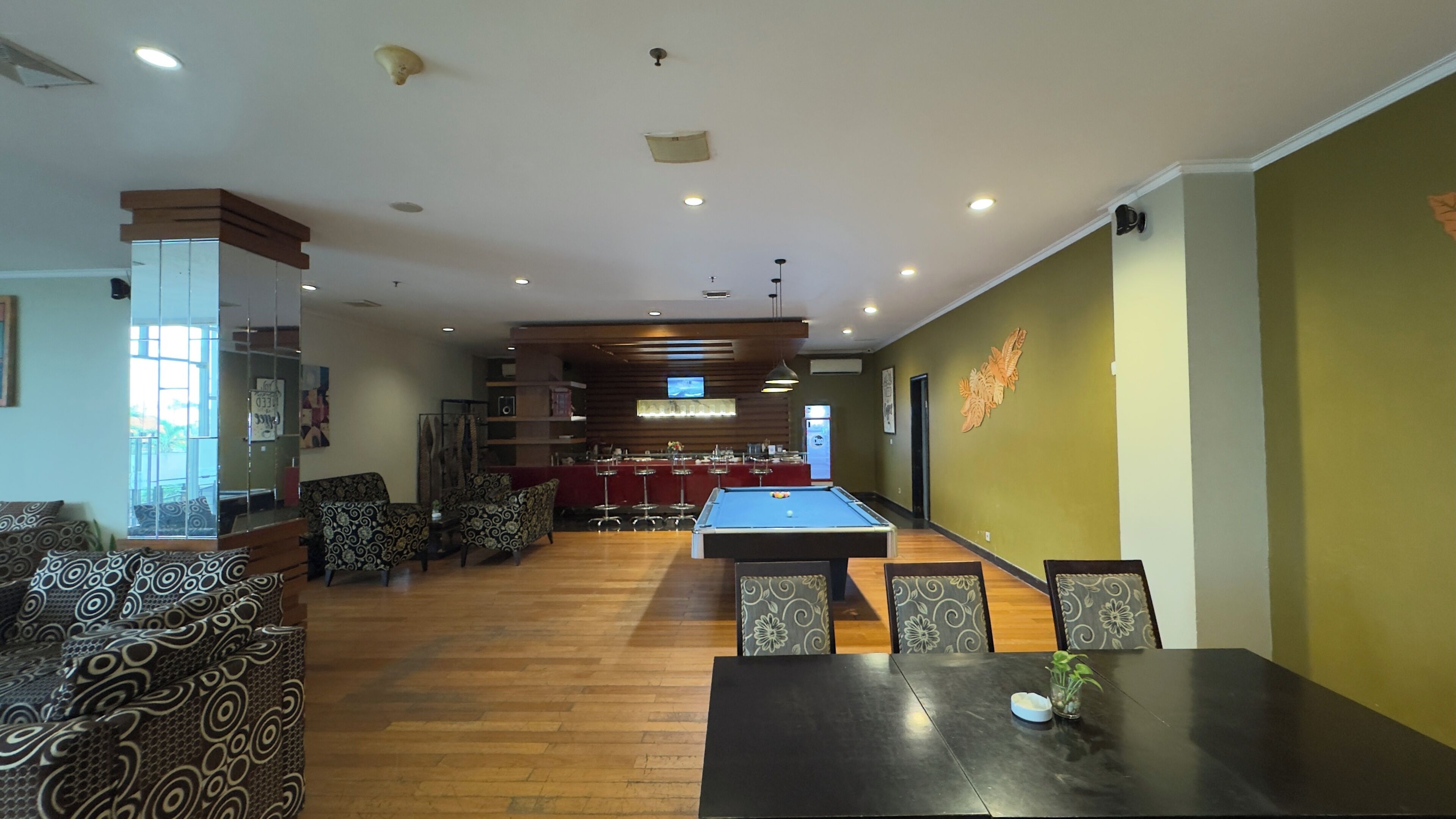 A room with a pool table, bar area, and seating.