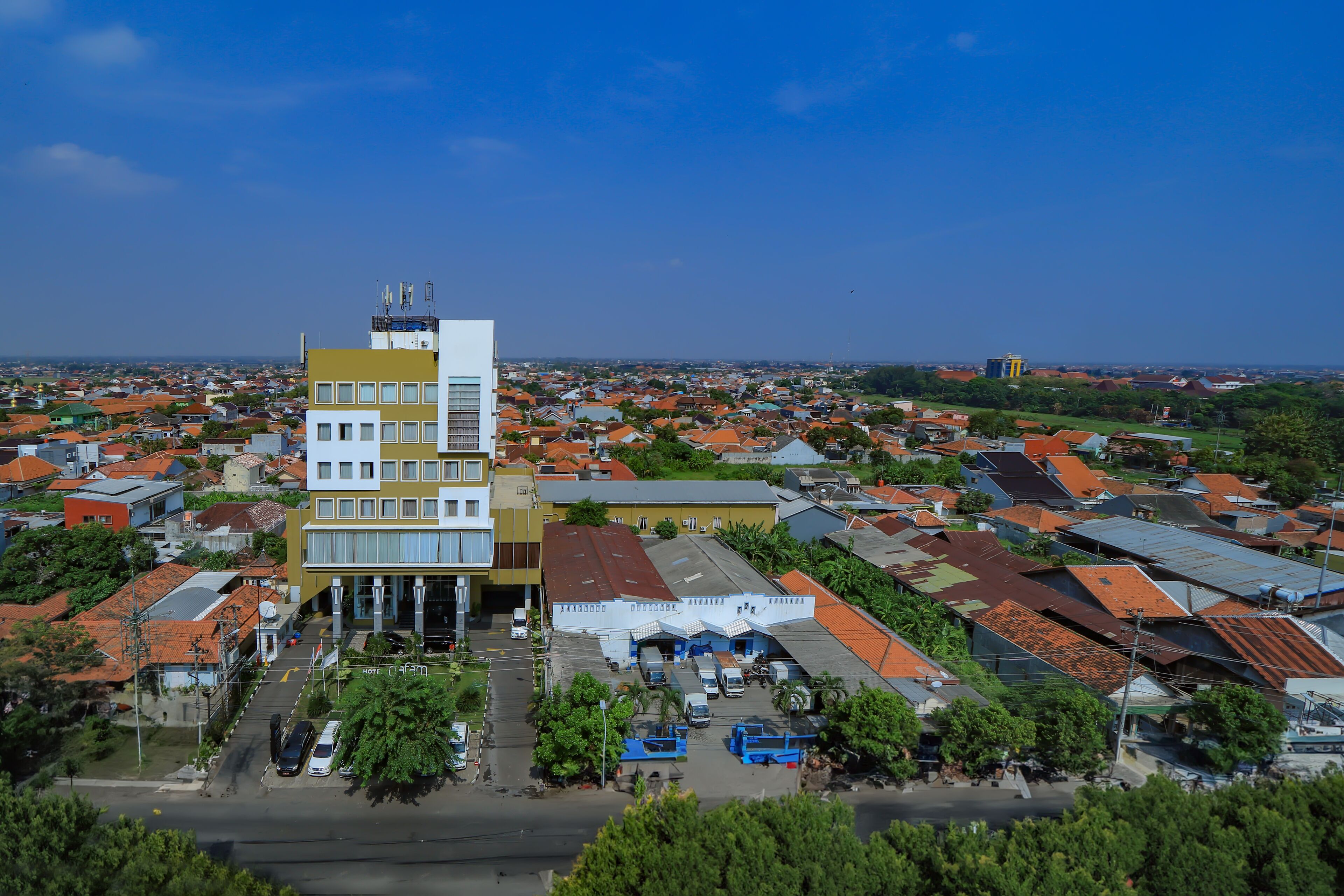 A multi-story building with a modern design, surrounded by a residential area with various roof colors.
