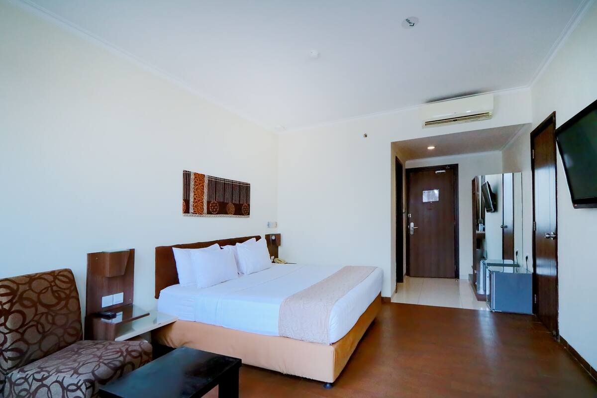 Ein Hotelzimmer mit Bett, Sofa, Schreibtisch und Fernseher.