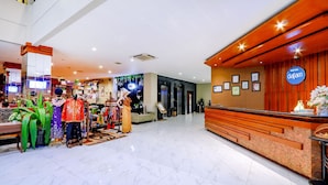 Un vestíbulo de hotel con una recepción, un área de descanso y una exhibición de trajes tradicionales coloridos.