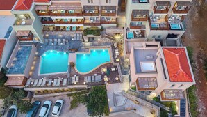 A multi-story hotel with a rooftop pool, outdoor seating areas, and a parking lot. - Mystery Skiathos Luxury Residence  (Skiathos)