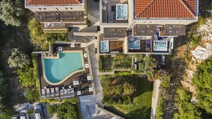 An aerial view of a resort with multiple hot tubs, a swimming pool, and a parking area. - Mystery Skiathos Luxury Residence  (Skiathos)