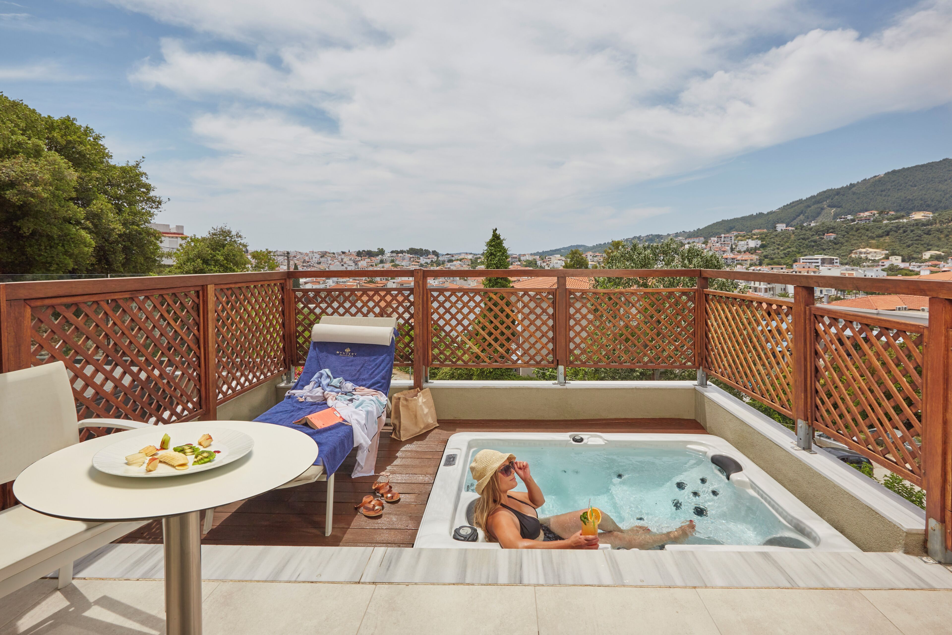 Une terrasse sur le toit équipée d’un jacuzzi, de chaises longues et d’une table où sont servis des plats.