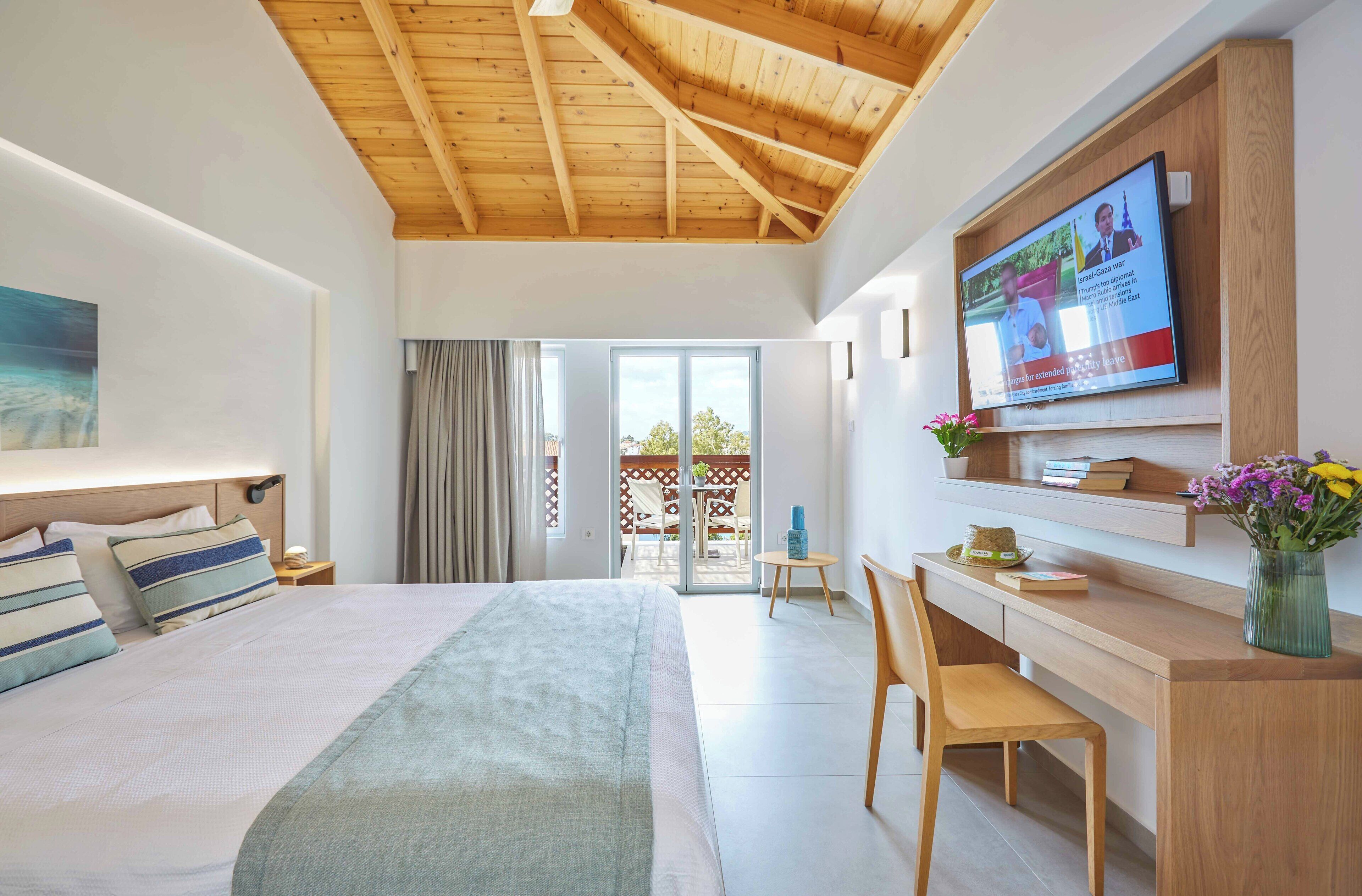 Ett modernt hotellrum med en säng, ett skrivbord, en TV och en balkong.